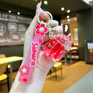 Macro detail of Sakura themed acrylic keychain with pink silicone strap and liquid charms