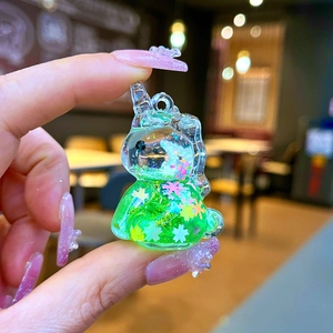 Close-up of a mini unicorn keychain charm with green liquid glitter and floral sequins