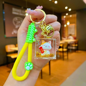 Detail of lucky cat acrylic keychain with yellow silicone wrist strap and liquid sand