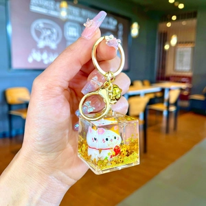 Detailed view of lucky cat cube keychain with gold glitter in clear resin charm