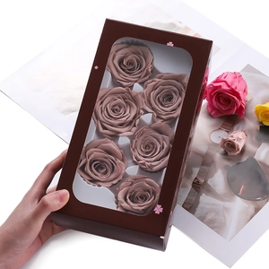 Detail of preserved mauve roses in a gift box with a transparent window held by hand