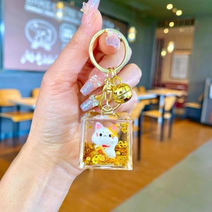 Lucky cat crystal keychain with flowing sand and golden bells in a square charm