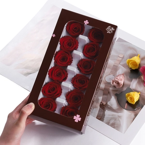 Detailed view of twelve preserved red roses in a gift box held by hand for decoration