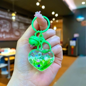 Detail of neon green heart liquid keychain with drifting glitter and matching bell charm