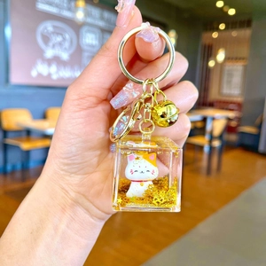 Close-up of creative Maneki Neko lucky cat liquid sand keychain with golden bell