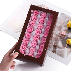 Close-up of pink preserved roses in a brown window gift box with elegant lifestyle props