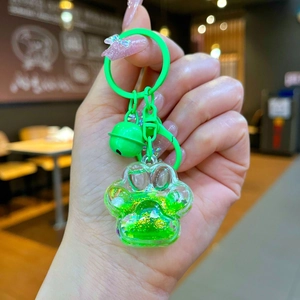 Détail d'un porte-clés patte de chat vert néon avec paillettes flottantes et sable mouvant