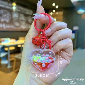 Detail shot of a heart-shaped liquid keychain with glitter and a red bell ornament