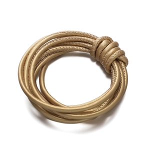 Close-up of golden braided PU leather cord bracelet with decorative woven knot detail