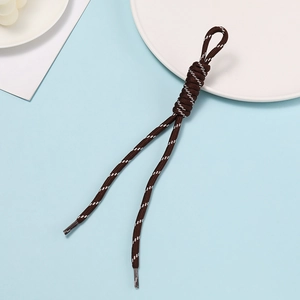 Detailed view of a brown woven paracord keychain with reflective white threads and knot