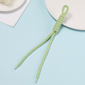 Detail of light green hand-woven rope with intricate knotting and clear plastic aglet