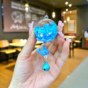 Detailed view of a whale-themed liquid glitter keychain with blue resin charm and metal bell
