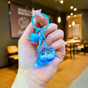 Detail of blue ice cream keychain with liquid glitter, small bell and plastic ring hook