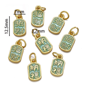 Détail de breloques porte-bonheur en émail vert et or mesurant 12,5 mm par 7 mm