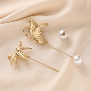 Detail view of gold butterfly and bamboo brooches with pearls on champagne silk fabric