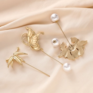 Detailed set of three gold-plated butterfly and floral pins on elegant champagne silk