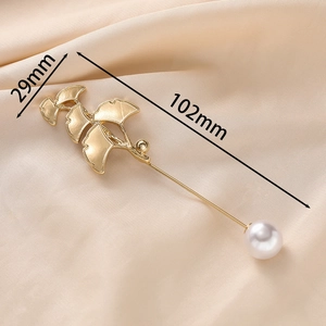 Elegant gold ginkgo leaf brooch with white pearl on champagne silk fabric background