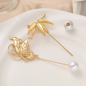 Elegant gold bamboo and butterfly brooch set with pearls on a white ceramic plate