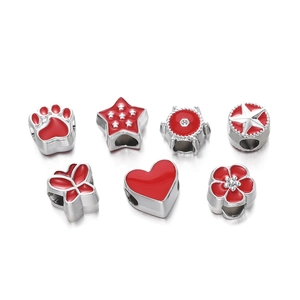 Macro detail of red enamel charm beads including heart, star, and flower shapes for DIY
