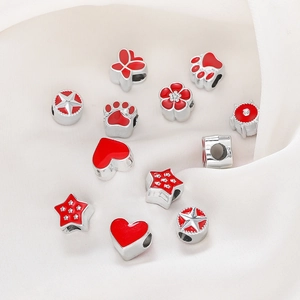 DIY jewelry beads with red enamel star and heart shapes on white fabric background
