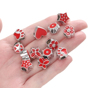 Macro detail of silver beads with red enamel hearts, stars, and claws for DIY jewelry