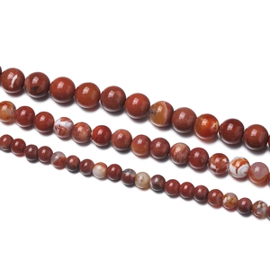 Macro detail of natural red agate beads in three sizes with polished finish and white stripes