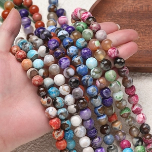 Multiple strands of natural tiger skin agate beads held by hand over a wooden tray
