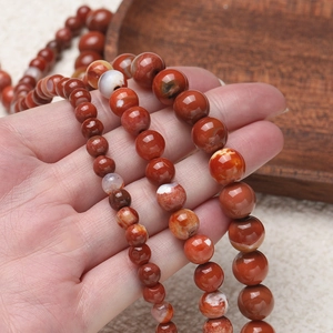 Detail of 6mm, 8mm, and 10mm natural red agate beads with smooth polished finish