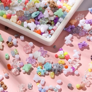 Assorted macaron colored acrylic beads including stars and flowers on a white tray