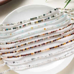 Détails macro de perles en pierre naturelle facettées multicolores sur assiette blanche