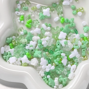 Close-up of mixed green acrylic DIY beads with stars, flowers and butterfly shapes