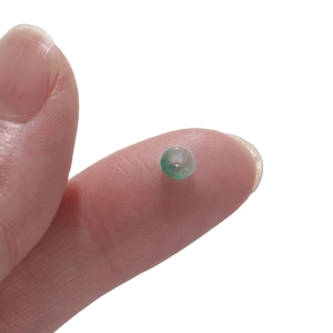 Makroaufnahme einer 2x4mm grünen Katzenaugen-Glasperle zwischen den Fingern zur Größe