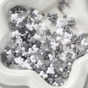 Macro shot of mixed acrylic DIY beads in grey and silver on a white ceramic tray