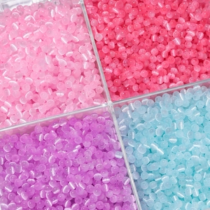 Makroaufnahme von 4mm Glas-Katzenaugenperlen in vier Farben in einer Kunststoff-Sortierbox