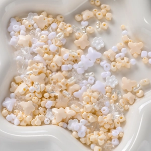 Close-up of mixed acrylic DIY beads in cream and white shapes in a decorative dish