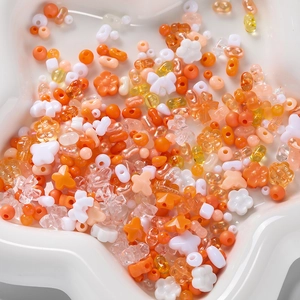Macro shot of assorted orange and peach acrylic beads in a star bowl for DIY jewelry