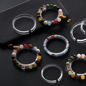 Detailed view of clear acrylic C-shaped bracelet display stands on a dark matte surface