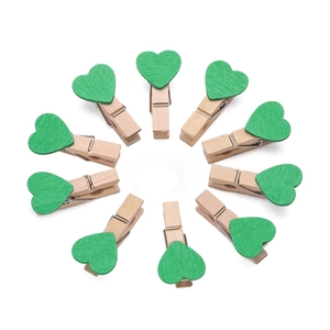Disposizione circolare di dieci mollette in legno con cuori verdi per decorazione di foto