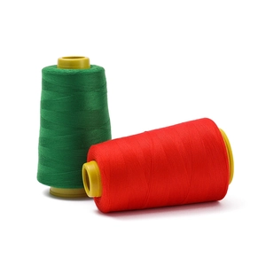 Close-up of red and green polyester sewing thread on yellow plastic bobbins for industrial use