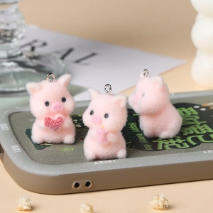 Detailed view of three cute pink flocked pig charms with heart and ice cream on a phone case