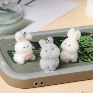 Macro detail of three cute flocked resin bunny charms on a green phone case cover