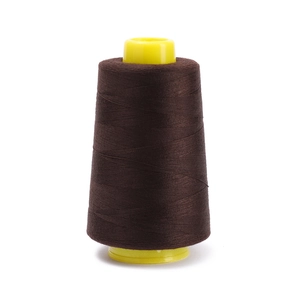 Macro shot of dark brown polyester sewing thread on yellow cone for sewing machines