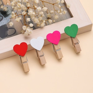 Macro di mollette in legno a cuore colorato con fiori secchi su sfondo beige