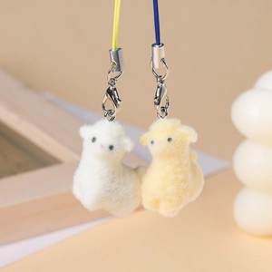Close-up of cute flocked alpaca pendants in white and yellow with metal lobster clasps