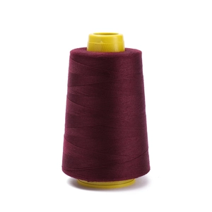 Detail of dark red polyester sewing thread on a yellow plastic cone for garment making