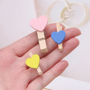 Primo piano di mollette in legno a cuore nei colori pastello rosa, blu e giallo per foto