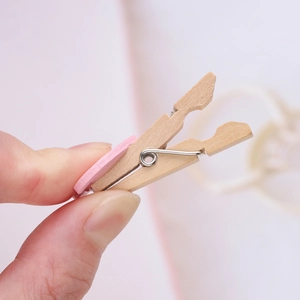 Primo piano di una piccola clip per foto in legno con un elemento decorativo a cuore rosa