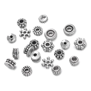 Vista macro de cuentas espaciadoras de aleación de plata con patrones florales y de engranajes