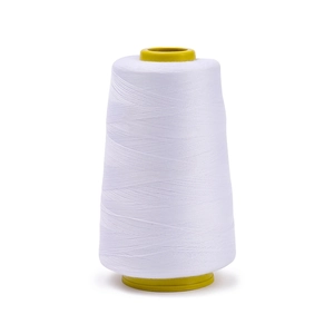 Detail of high-strength white polyester sewing thread on yellow plastic spool for machines