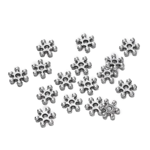 Vista macro de cuentas espaciadoras de copo de nieve plateadas vintage para joyería artesanal